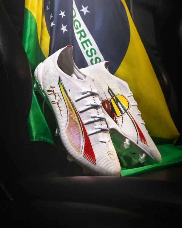 Puma Ultra x Senna Football Boots, depicted in front of Brazil's national flag. 